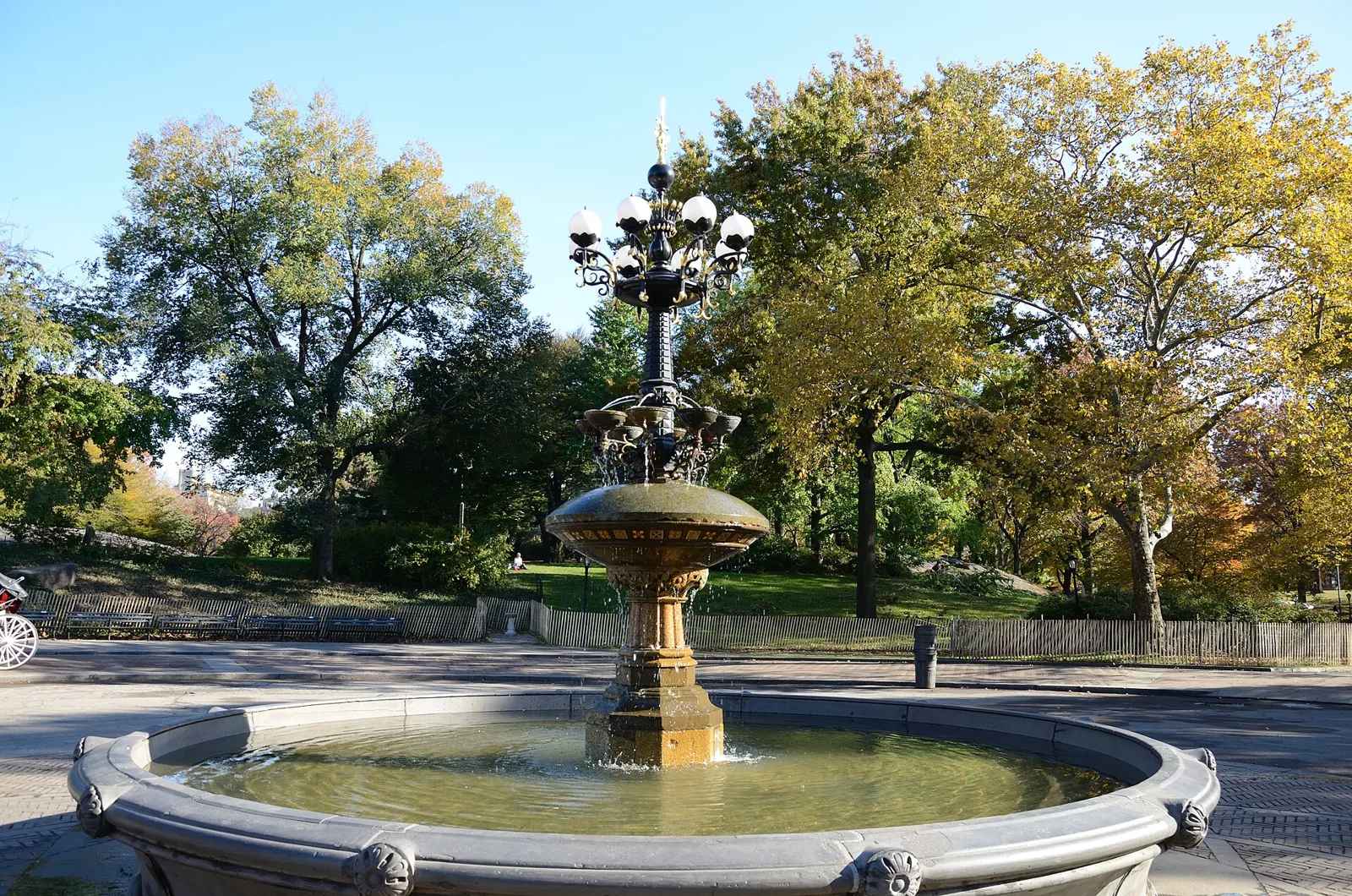 Cherry Hill Fountain with its ornate lamp at the top, surrounded by autumn trees in Central Park