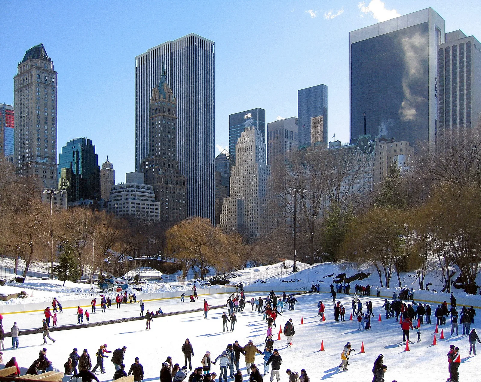 Skaters on Wollman Rink in Central Park with the Midtown skyline behind it in winter