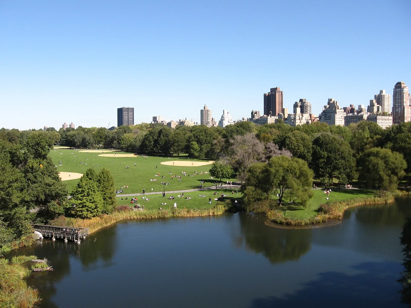 The Great Lawn and a pond in Central Park seen from Belvedere Castle, with city buildings beyond
