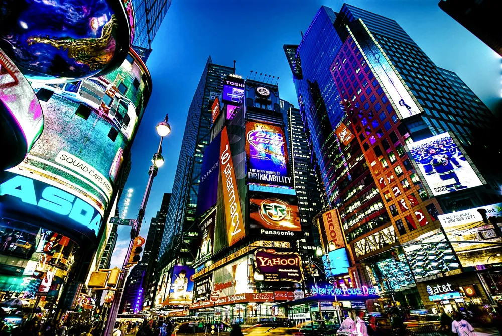 Times Square at dusk, lit by giant screens and neon signs