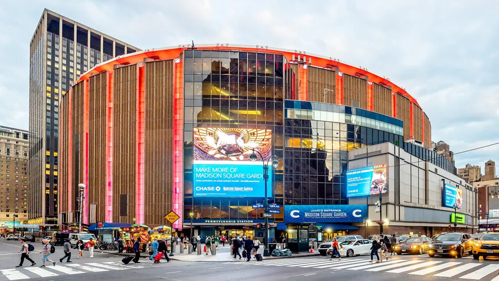 Madison Square Garden at dusk with pedestrians crossing the street in front