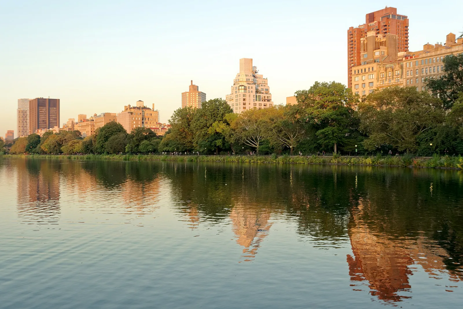 The Jacqueline Kennedy Onassis Reservoir in Central Park at sunset, with Upper East Side buildings reflected in the water